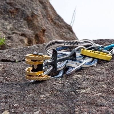 Cams, slings and carabiners resting on granite at the base of a climb.